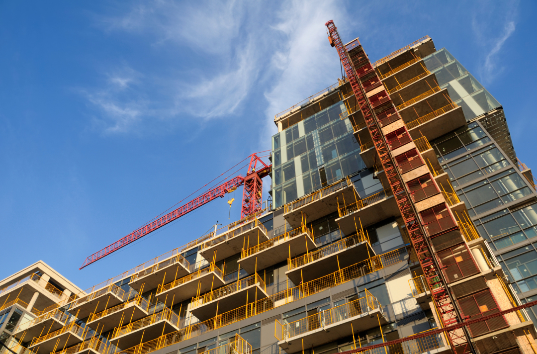 high-rise construction image taken looking up at an angle showing a crane